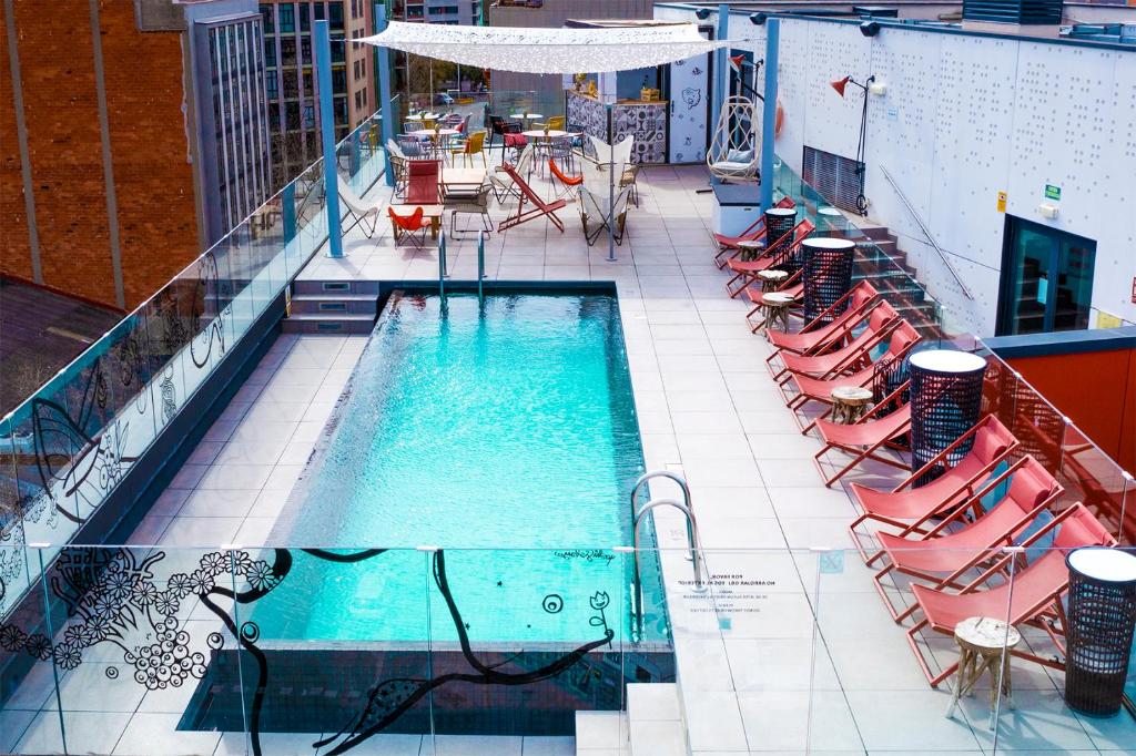 a swimming pool with chairs and tables on a building at ibis Styles Barcelona City Bogatell in Barcelona