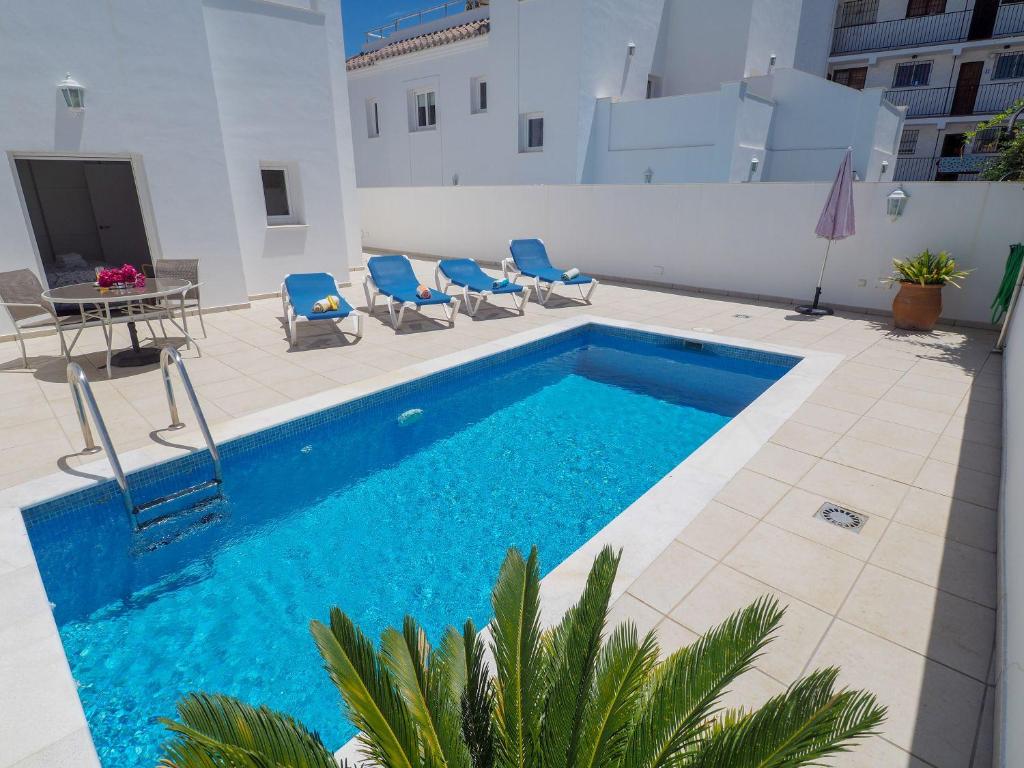 a swimming pool with chairs and a table next to a building at Nerja Paradise Rentals - Villa Ambar in Nerja