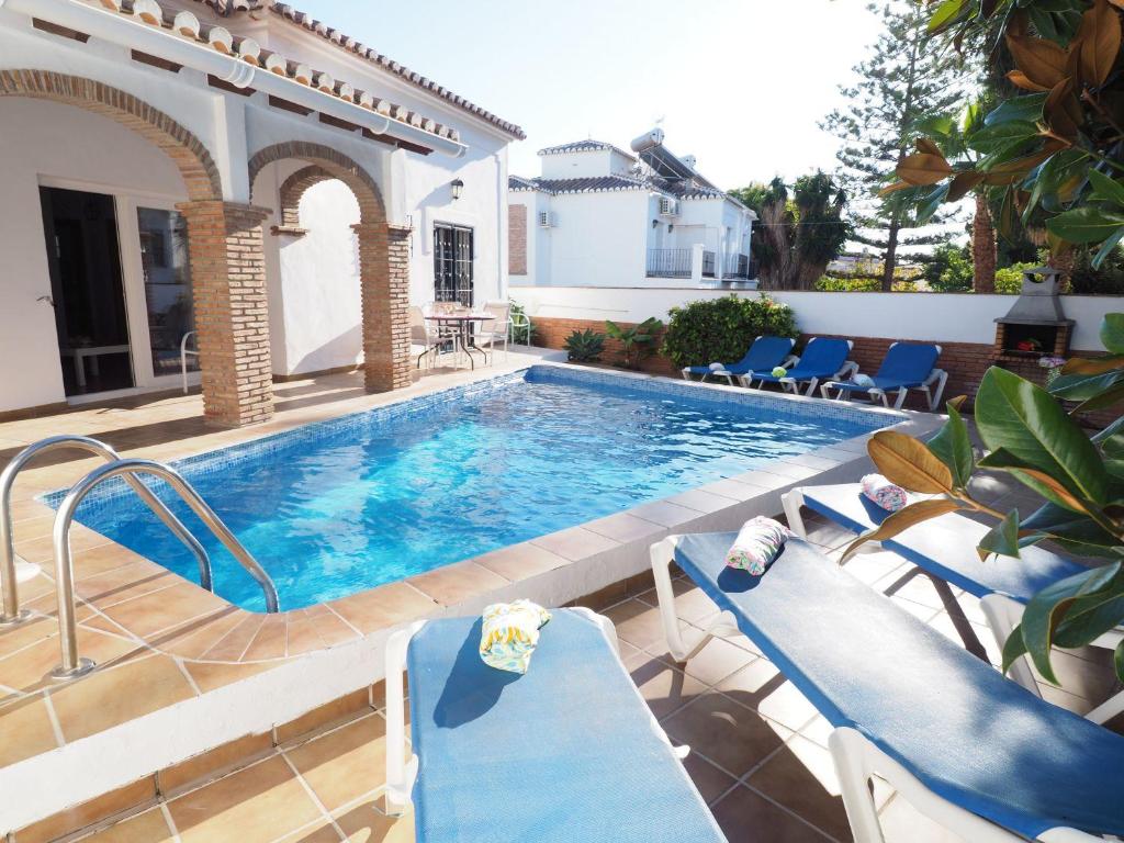 een zwembad met blauwe stoelen naast een huis bij Nerja Paradise Rentals - Villa Jazmines in Nerja