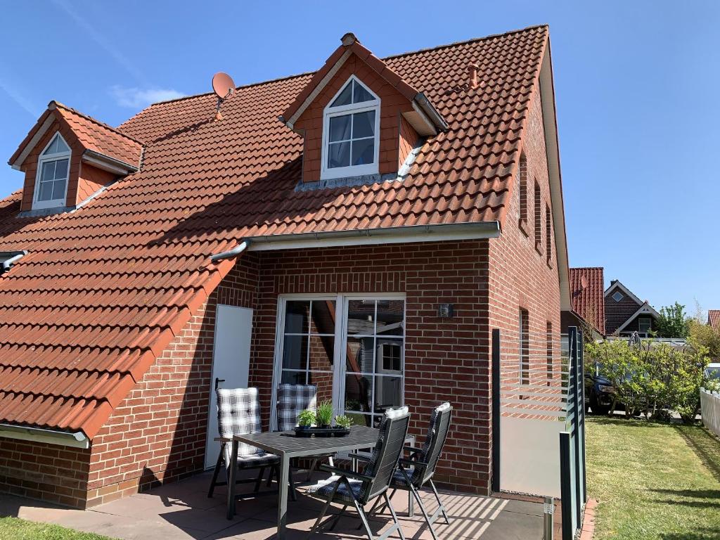 una casa de ladrillo con una mesa y sillas en un patio en Nordseemuschel, en Norddeich