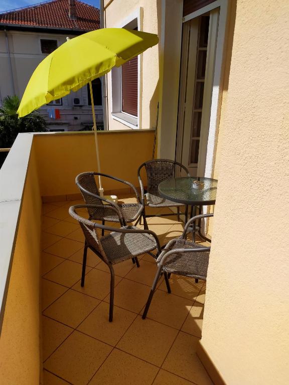 a table and chairs with a yellow umbrella on a balcony at Apartments Ivna Bilek in Opatija