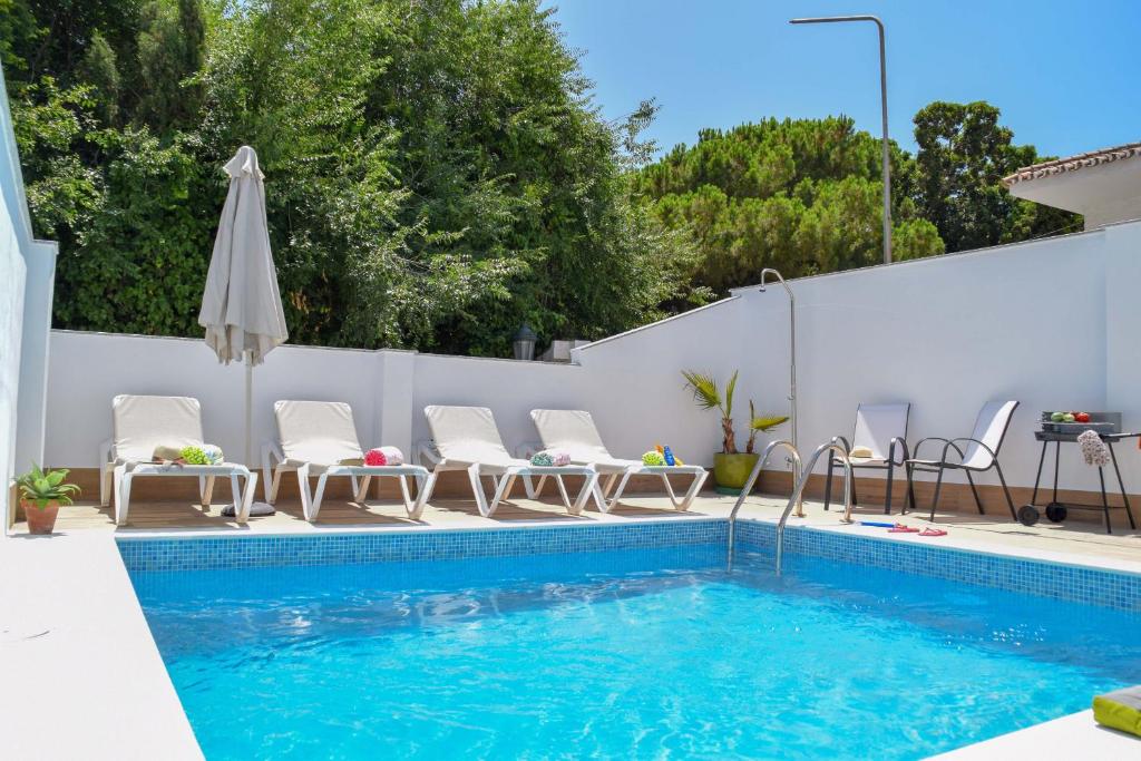 - une piscine avec des chaises et un parasol à côté d'une clôture dans l'établissement Nerja Paradise Rentals - Villa Valeria, à Nerja