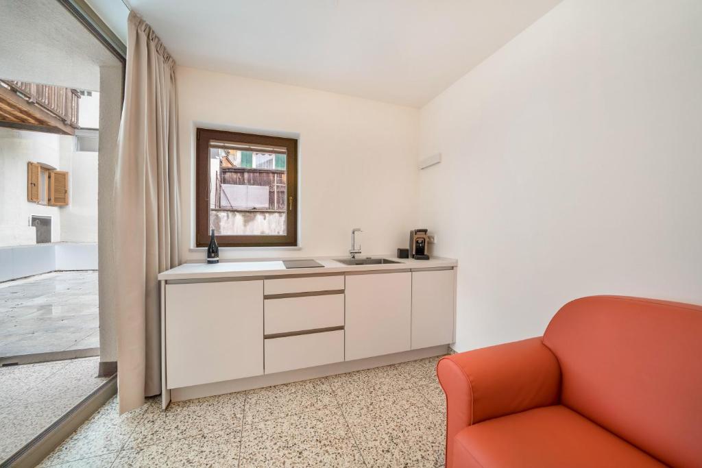 eine Küche mit einem Waschbecken und einem orangefarbenen Sofa in der Unterkunft Domus Faber 2a in Meran
