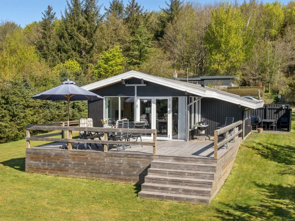 a house with a deck with a table and an umbrella at Holiday Home Matilde - 400m to the inlet by Interhome in Struer