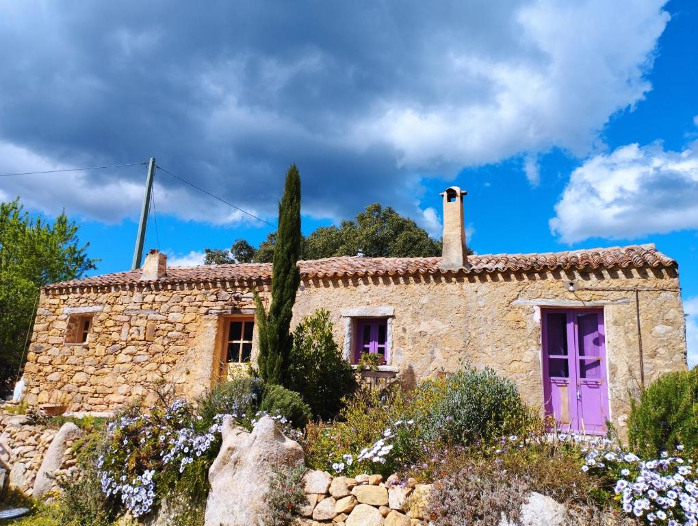 una vieja casa de piedra con una puerta morada en holiday home su Niberalzu en Monti