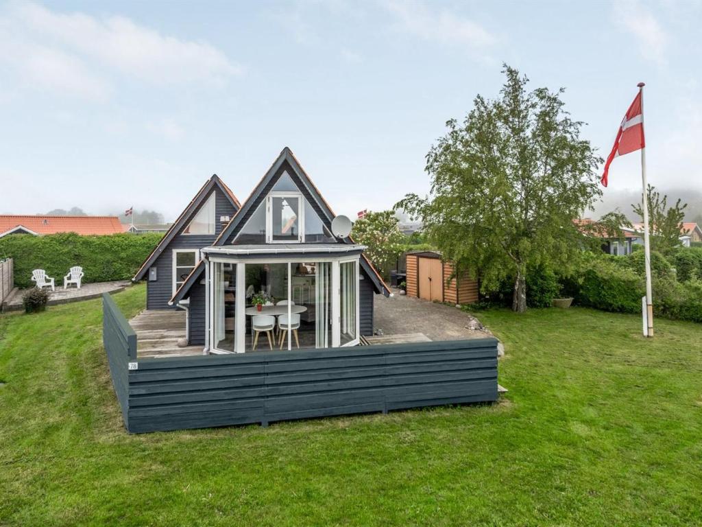 uma pequena casa na relva com uma bandeira em Holiday Home Leve - 200m from the sea in SE Jutland by Interhome em Sønderby
