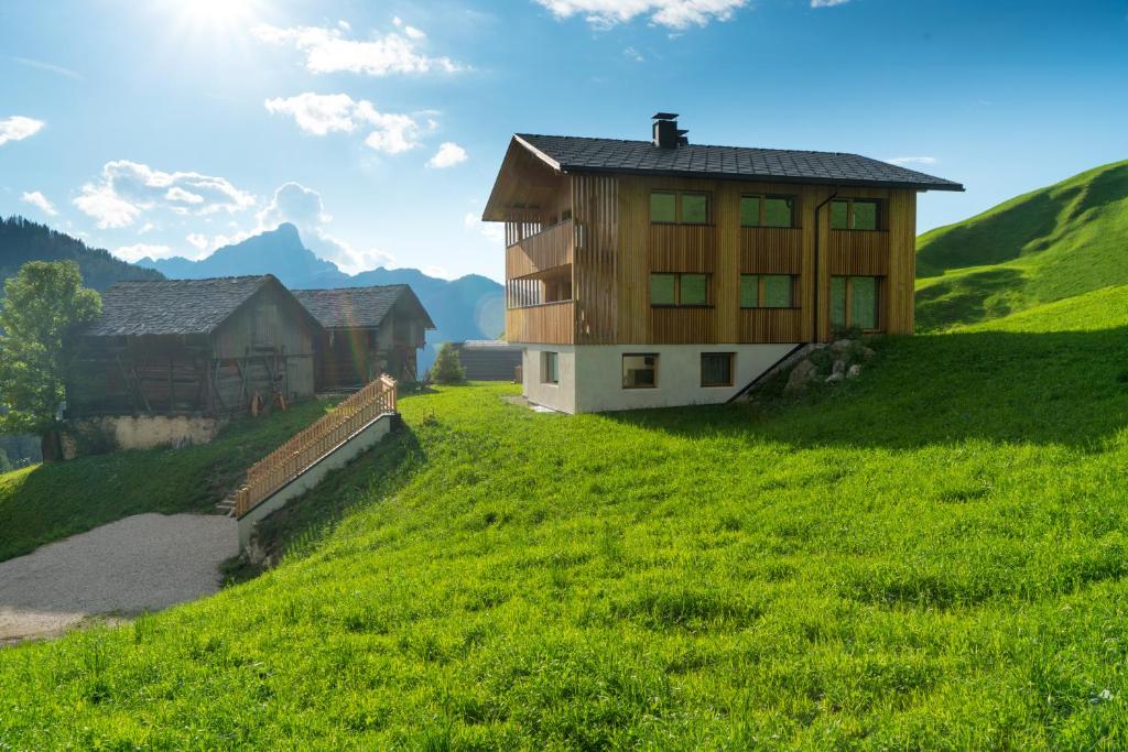 una casa en una colina con un campo verde en Ciasa Plandros Apartments, en La Valle