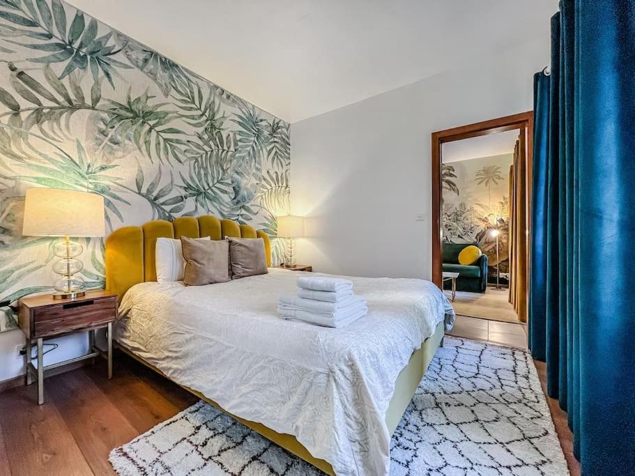 a bedroom with a king sized bed with a tropical wallpaper at Quiet & Comfy apartment on Av du Casino in Montreux