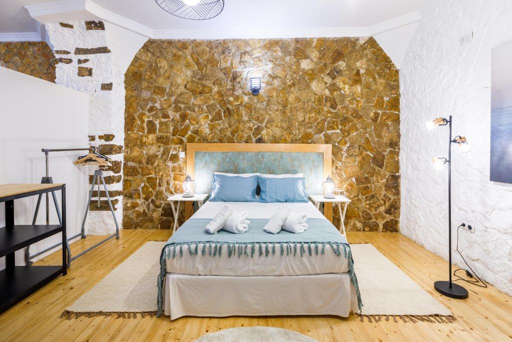 a bedroom with a bed and a stone wall at Galeria Guesthouse in Tavira