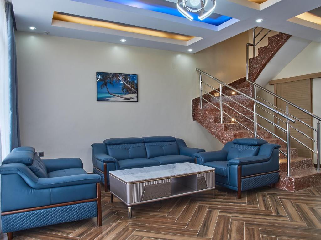 a waiting room with blue couches and a tv at Unique Apartment in Kigali