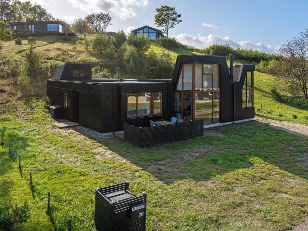 una casa negra sentada en la cima de un campo de hierba en Holiday Home Fritze - 400m from the sea in Djursland and Mols by Interhome, en Glesborg