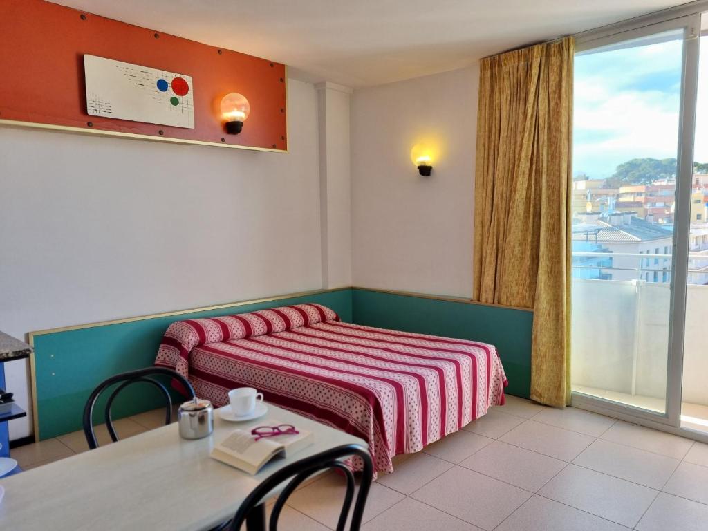 リョレート・デ・マルにあるApartments Lloret Sunのベッド2台、テーブル、窓が備わる客室です。