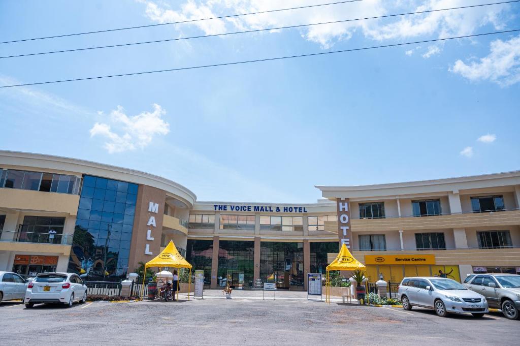 un gran edificio con coches estacionados frente a él en The Voice Hotel, en Entebbe