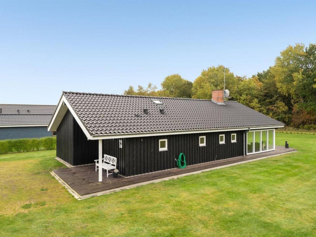 a black building with a deck in a yard at Holiday Home Femke - 250m to the inlet in NE Jutland by Interhome in Storvorde