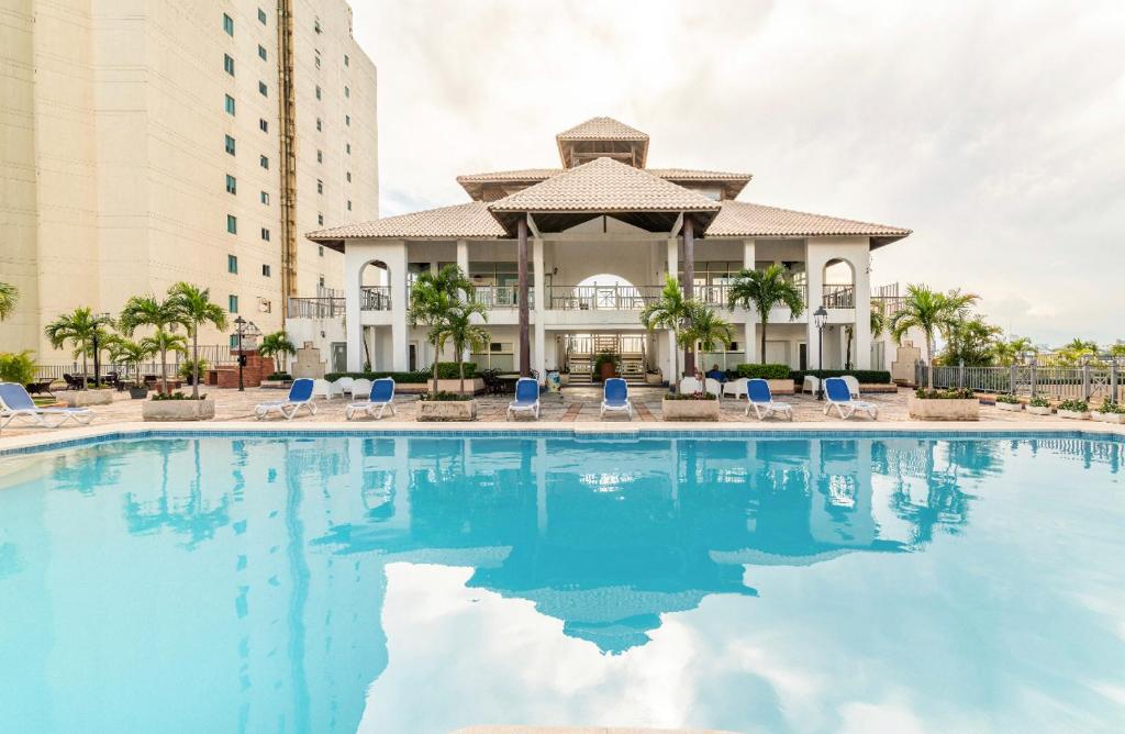 una gran piscina con sillas azules y un edificio en Exclusive 3 BDR, Gym & Pool, SeaView, Luxury Tower, en Santo Domingo