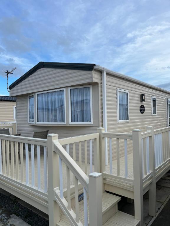a mobile home with a porch and a fence at Golden Palm Resort PG163 in Chapel Saint Leonards