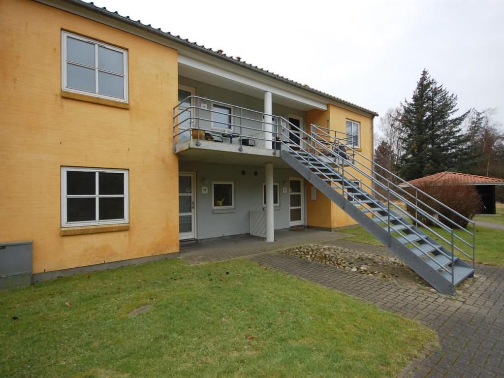 une maison jaune avec un escalier devant elle dans l'établissement Apartment Runhild - 100m from the sea in NE Jutland by Interhome, à Hals