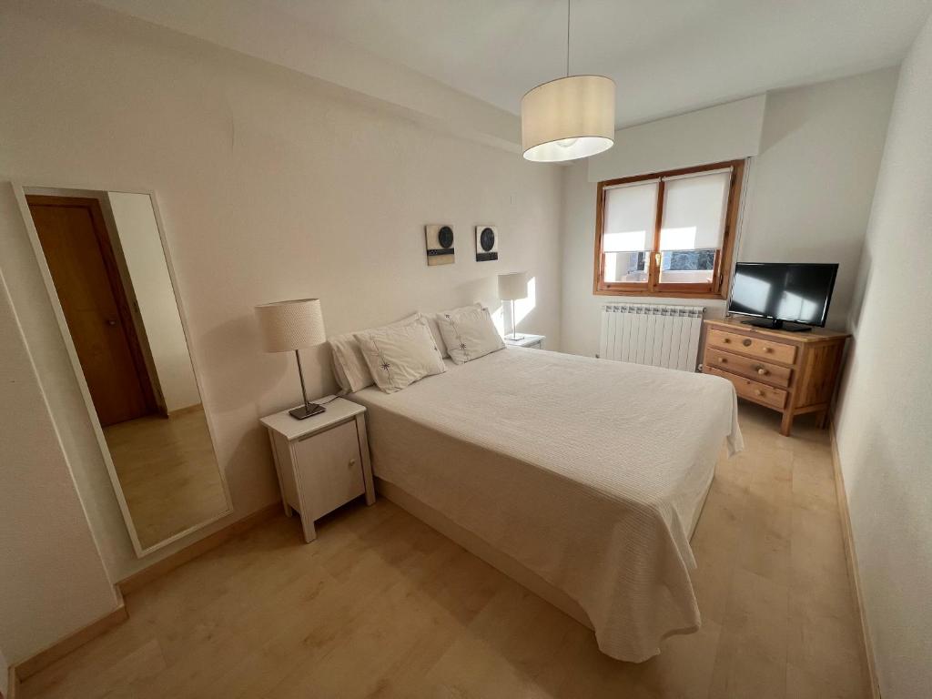 Schlafzimmer mit einem weißen Bett und einem TV in der Unterkunft Apartamento Muga in Jaca