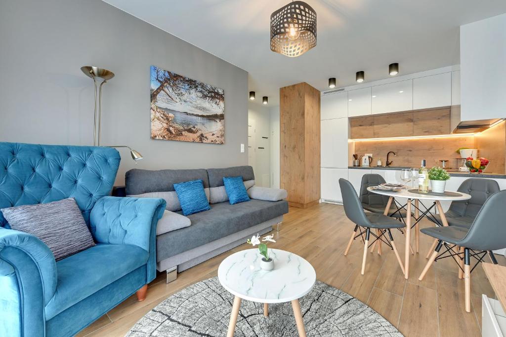 - un salon avec un canapé bleu et une table dans l'établissement Comfort Apartments Kopernika, à Gdynia