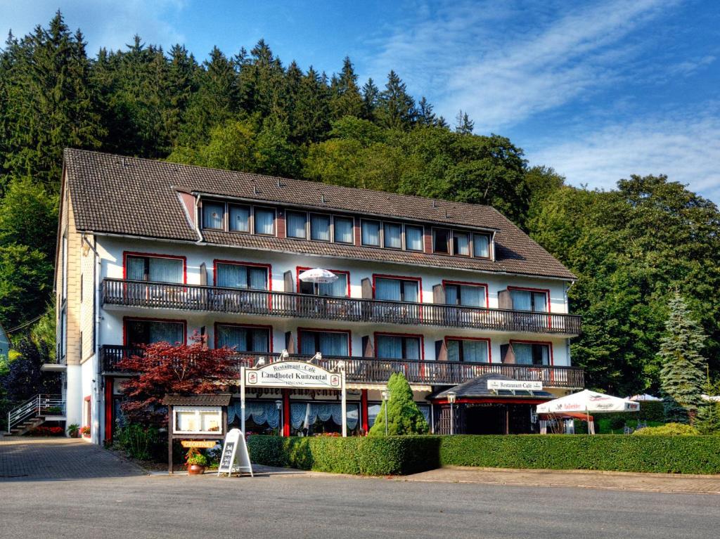 a large building with a balcony in front of a mountain at Landhotel Kunzental in Zorge