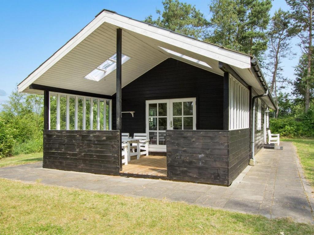 ein schwarzes Cottage mit einer Veranda und einer Terrasse in der Unterkunft Holiday Home Gaetana - 1-6km from the sea in NE Jutland by Interhome in Hals