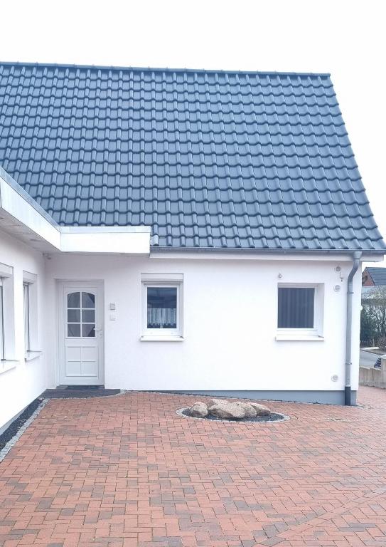 a white house with a black roof and a brick driveway at Fewo Voßeler in Büsum