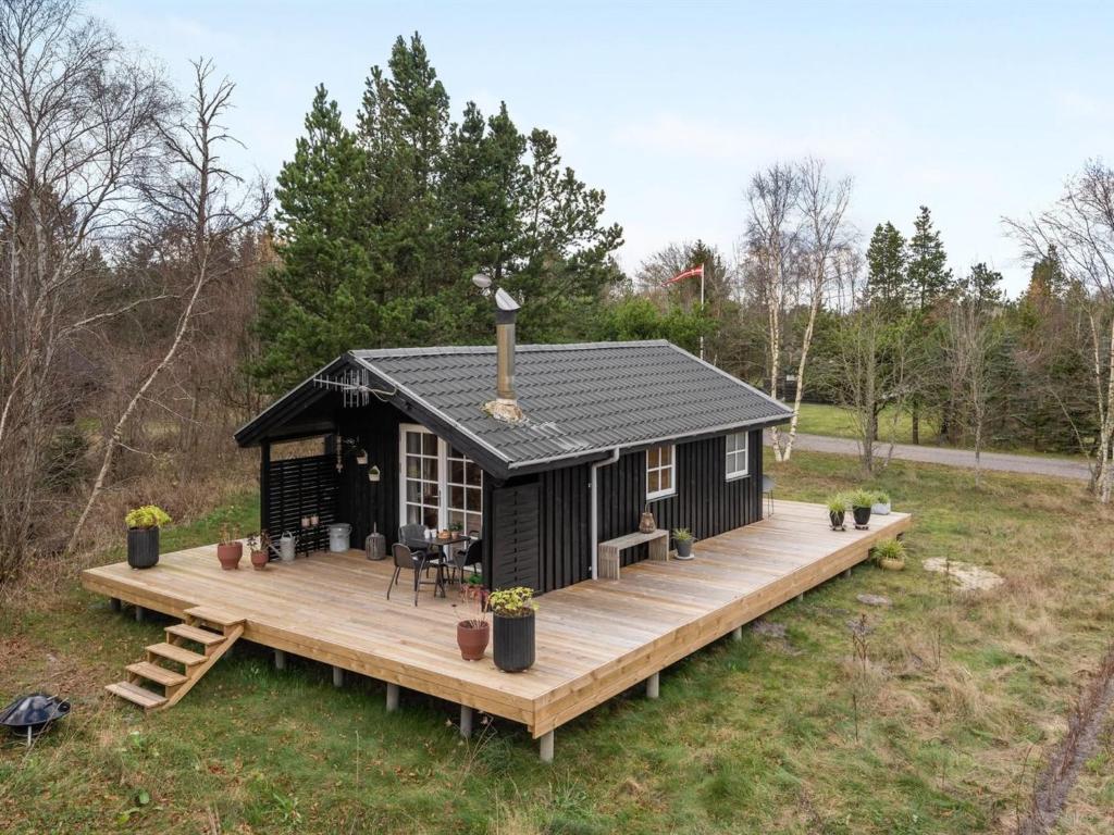 a black tiny house with a wooden deck at Holiday Home Imma - from the sea in NE Jutland by Interhome in Hals