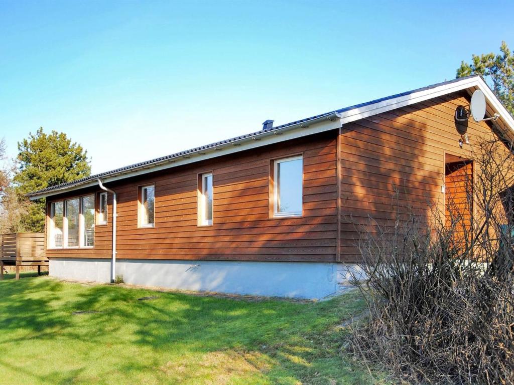 una casa de madera con un patio delante en Holiday Home Hristijan - 300m to the inlet in The Liim Fiord by Interhome, en Løgstør