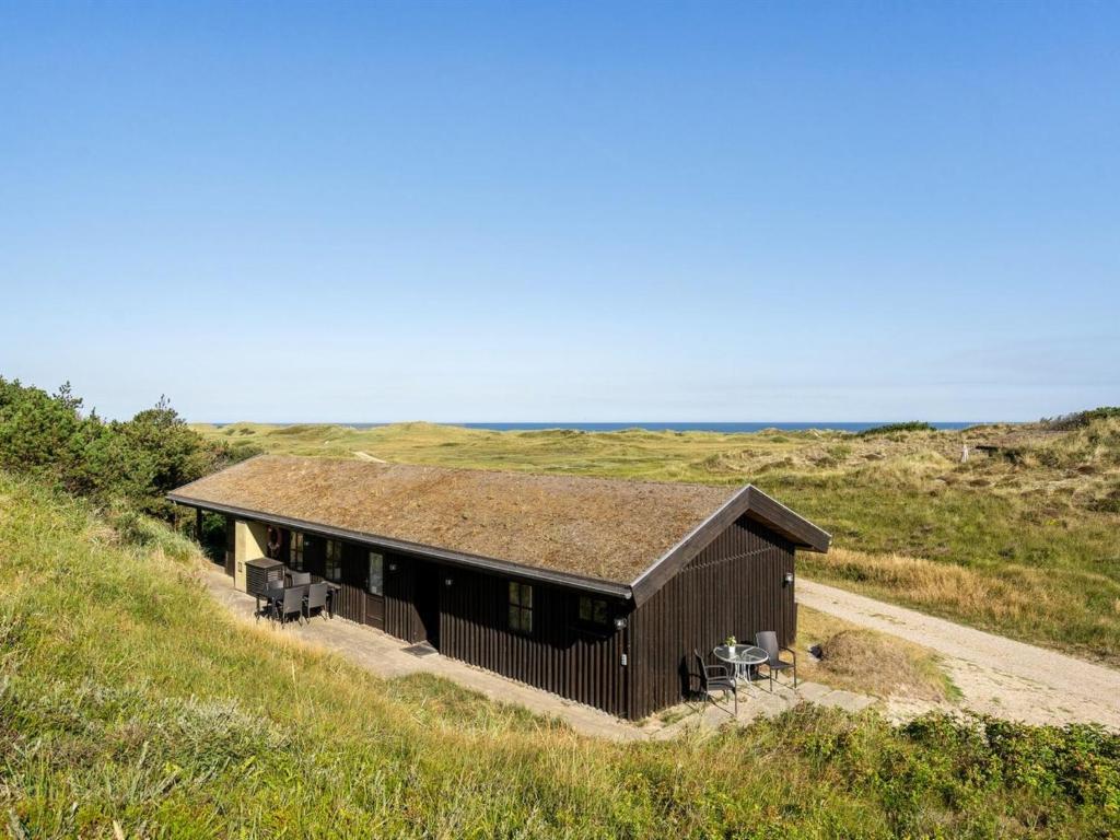 Holiday Home Marite - 200m from the sea in NW Jutland by Interhome في Pandrup: مبنى صغير بسقف عشبي على تلة