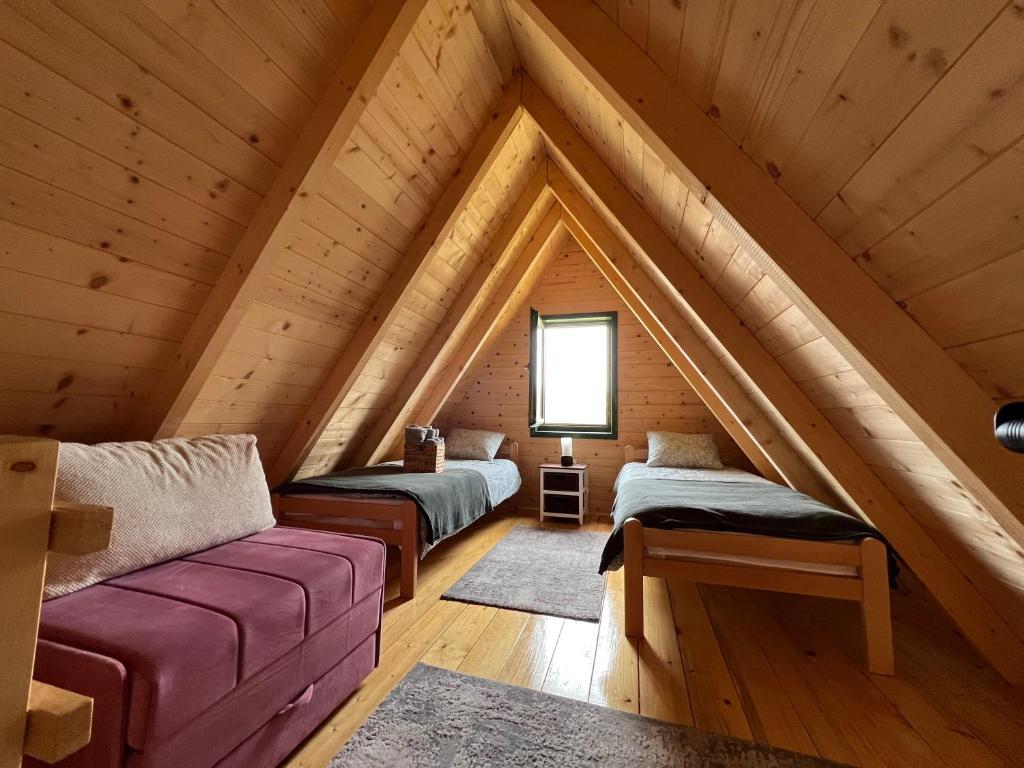 a attic room with two beds and a couch at Brvnare Puljci in Nova Varoš