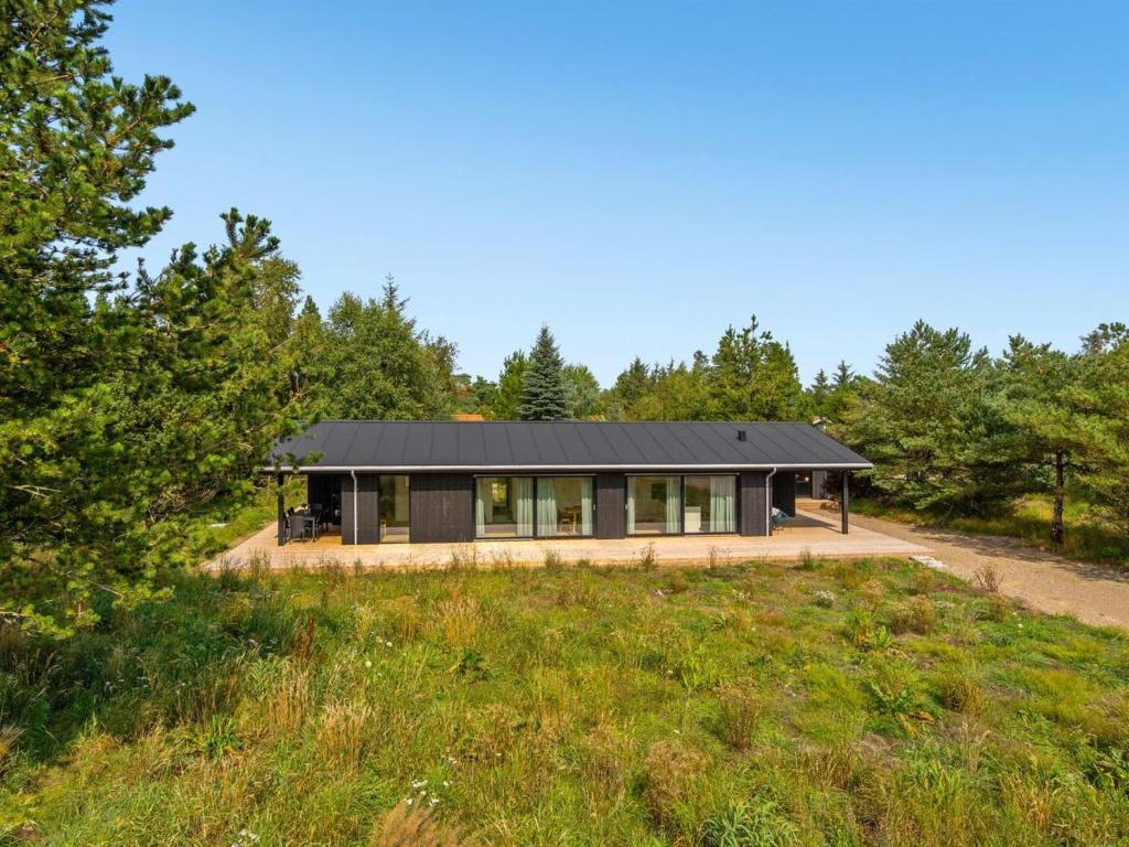 ein schwarzes Haus auf einem Hügel mit Bäumen in der Unterkunft Holiday Home Vigga - 800m from the sea in NW Jutland by Interhome in Fjerritslev