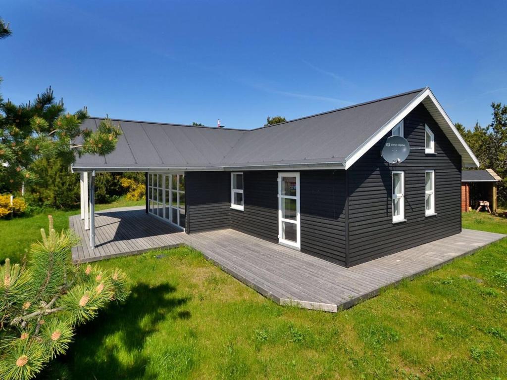 een zwart huis met een terras in een tuin bij Holiday Home Anethe - 100m to the inlet in The Liim Fiord by Interhome in Løgstør