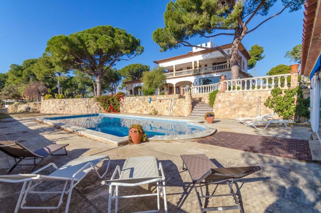 un hombre sentado en sillas junto a una piscina en Club Villamar - Alvent, en Banyeres del Penedés