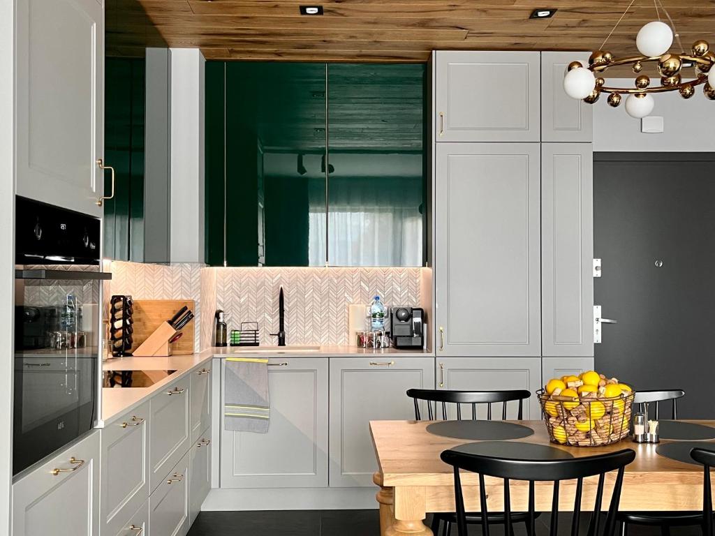 a kitchen with white cabinets and a table with chairs at Apartament Hawkinsa in Jelenia Góra
