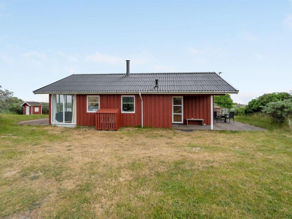 czerwony dom na polu z ogródkiem w obiekcie Holiday Home Stella - 700m from the sea in NW Jutland by Interhome w mieście Hjørring