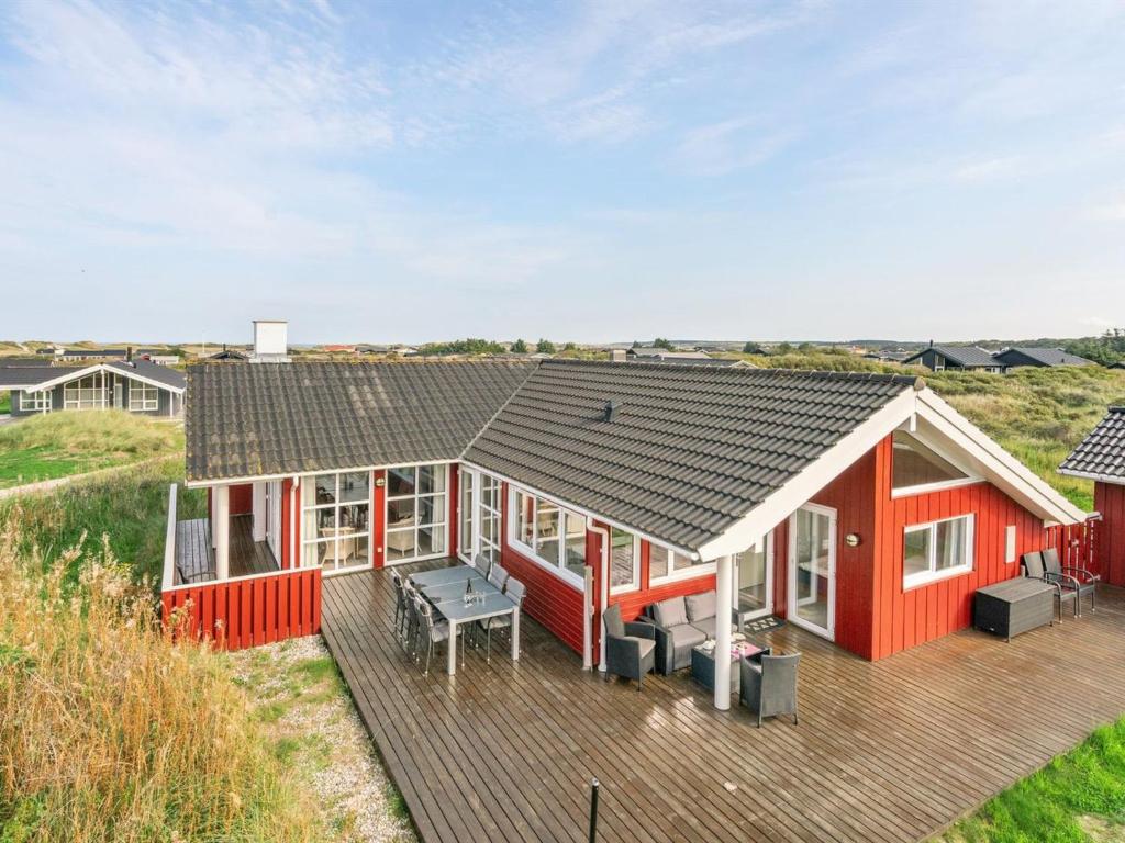 een rood huis met een terras bij Holiday Home Iacobus - 400m from the sea in NW Jutland by Interhome in Hjørring