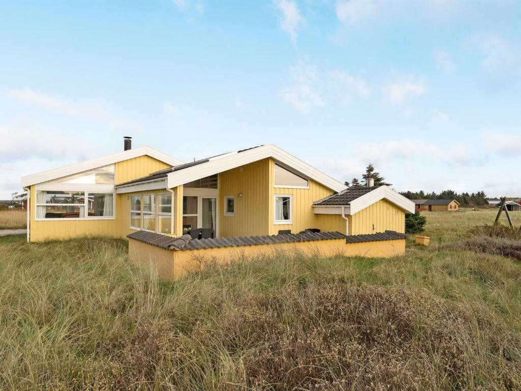 una casa amarilla en medio de un campo en Holiday Home Thorir - 300m from the sea in NW Jutland by Interhome, en Hirtshals