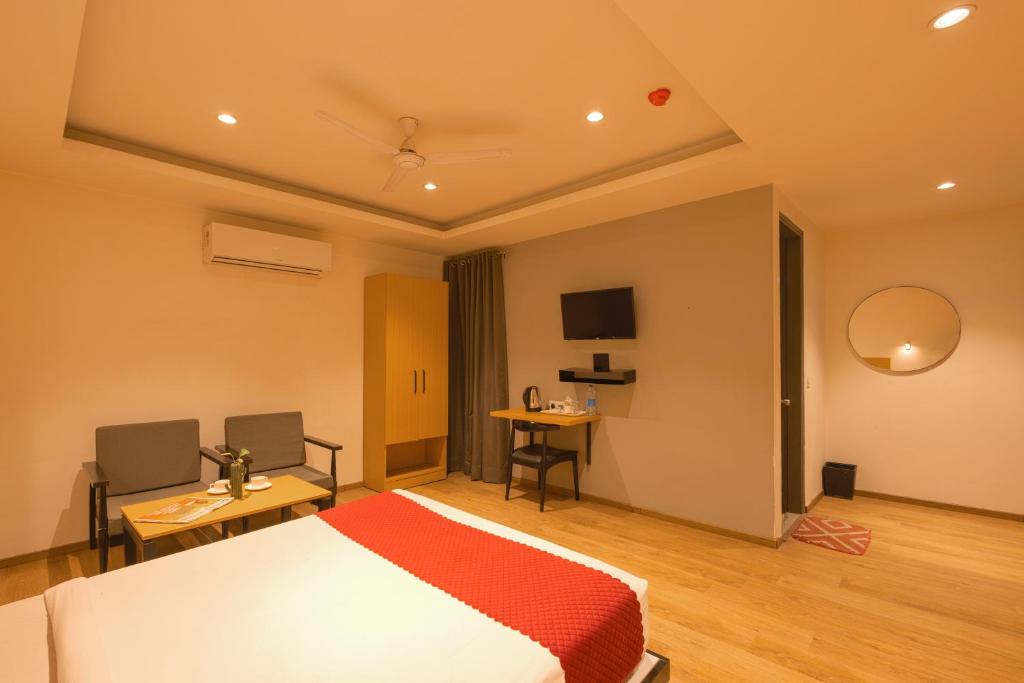 a bedroom with a bed and a table and a tv at The Grand Tashree at Delhi Airport in New Delhi