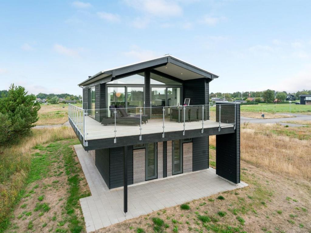 a black house with a deck on a field at Holiday Home Anabel - 500m from the sea in NE Jutland by Interhome in Frederikshavn