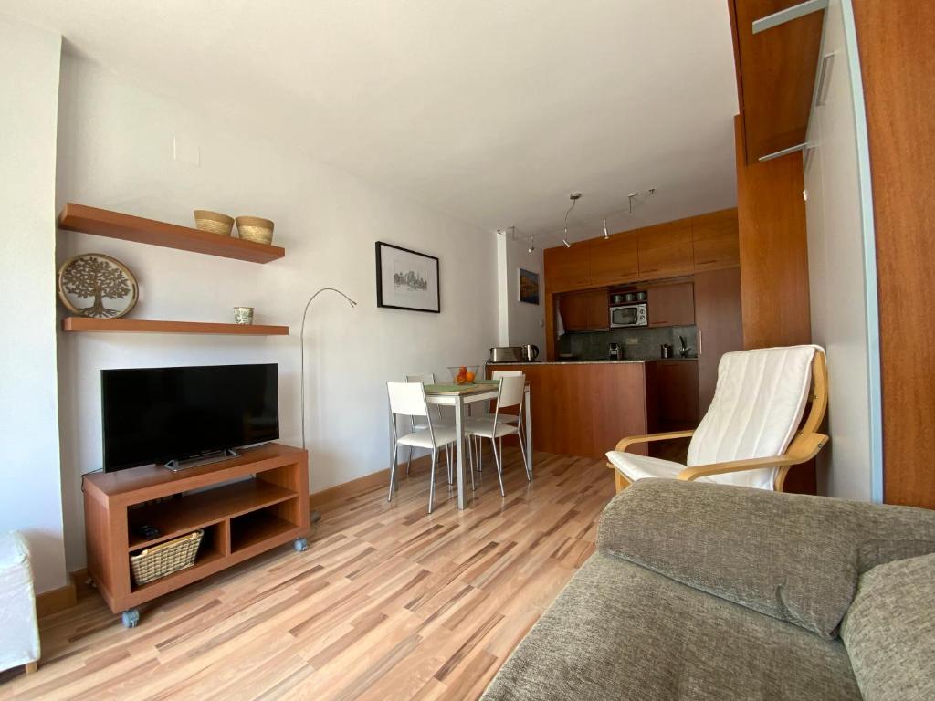 sala de estar con TV y mesa con sillas en LETS HOLIDAYS Quiet apartment with pool in tossa en Tossa de Mar