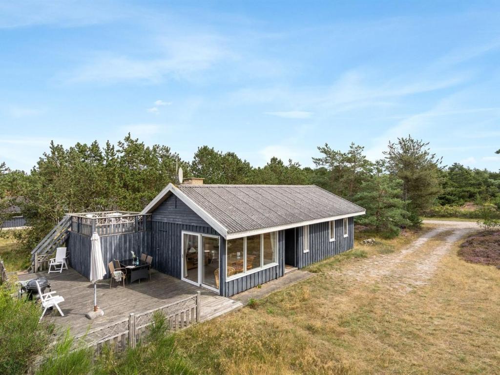 a black house with a deck in a field at Holiday Home Asmara - 200m from the sea in NE Jutland by Interhome in Læsø