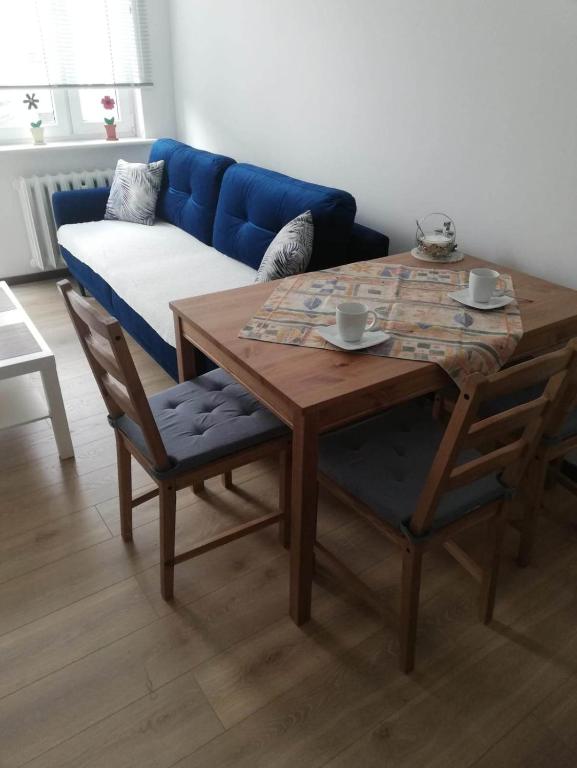 a living room with a table and a blue couch at Apartamencik Perełka in Skoczów