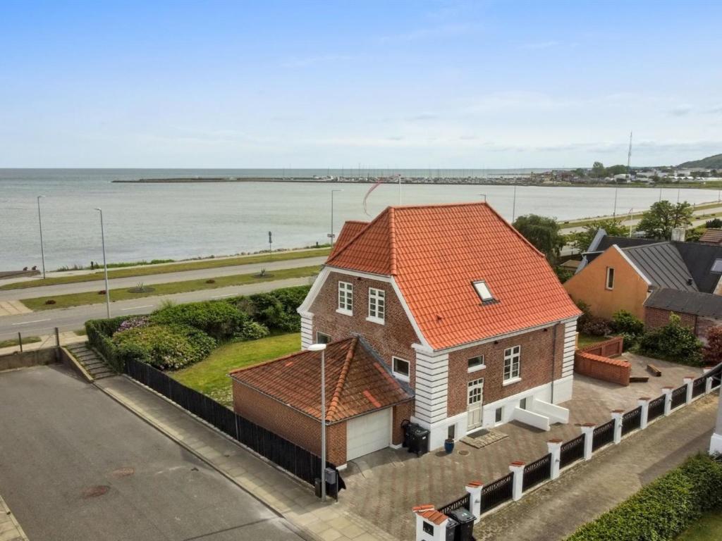 a house with an orange roof next to the water at Holiday Home Kosara - 50m from the sea in NE Jutland by Interhome in Frederikshavn