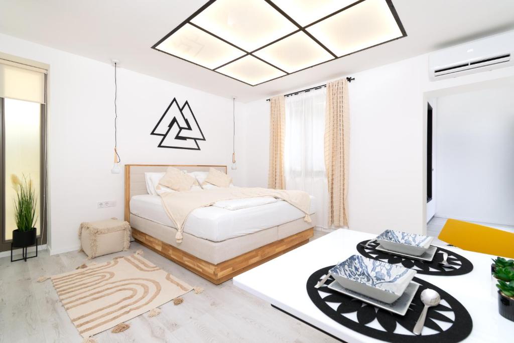 ein weißes Schlafzimmer mit einem Bett und einem Kronleuchter in der Unterkunft szolid in Miskolc