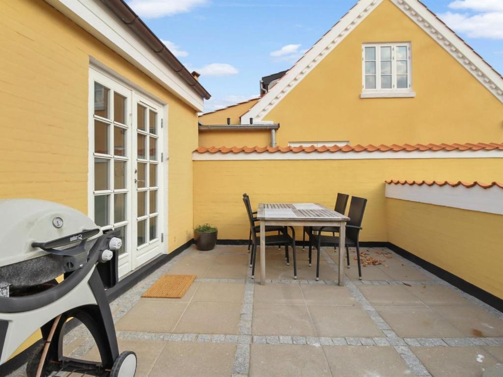 a patio with a table and chairs in front of a yellow house at Apartment Alkmund - 800m from the sea in NW Jutland by Interhome in Skagen