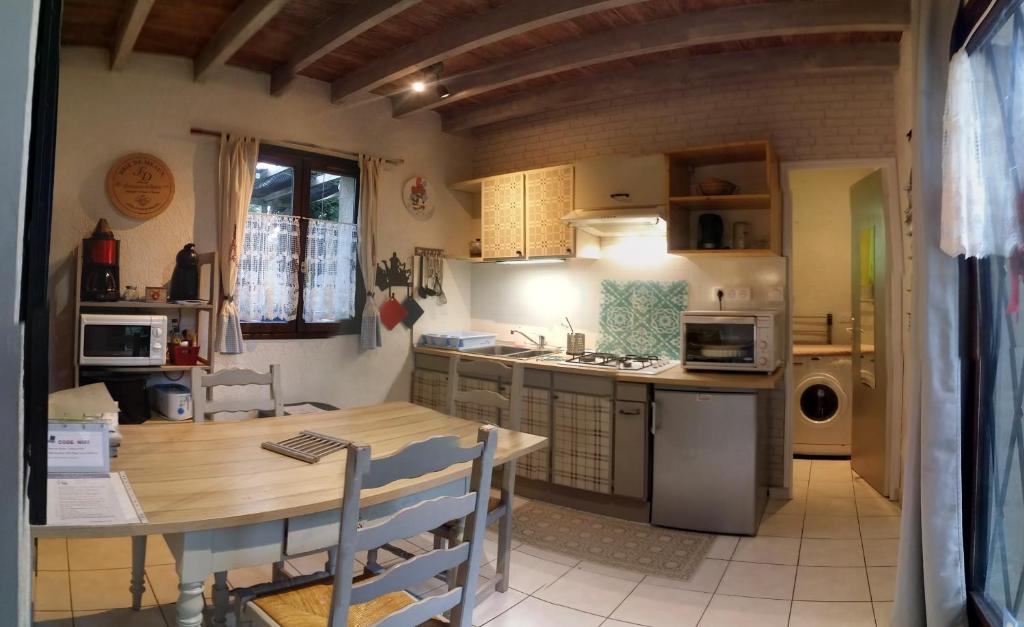 a kitchen with a table and a table and a dining room at Les Nympheas, appart, grand jardin au calme, parking gratuit,15 min Disneyland, in Crécy-la-Chapelle