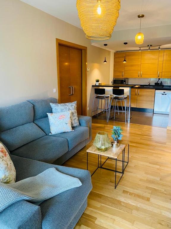 a living room with a blue couch and a kitchen at Apartamento Aldeana in Llanes