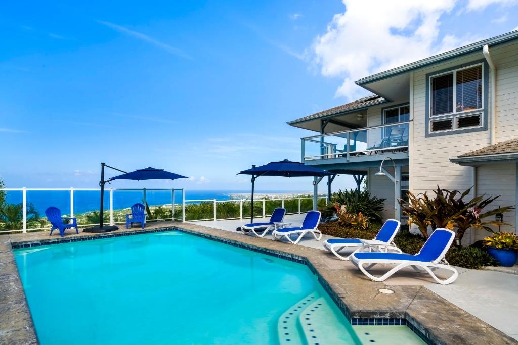 una piscina con sillas y sombrillas junto a una casa en Honu O Kai turtle Of The Sea, en Kailua-Kona