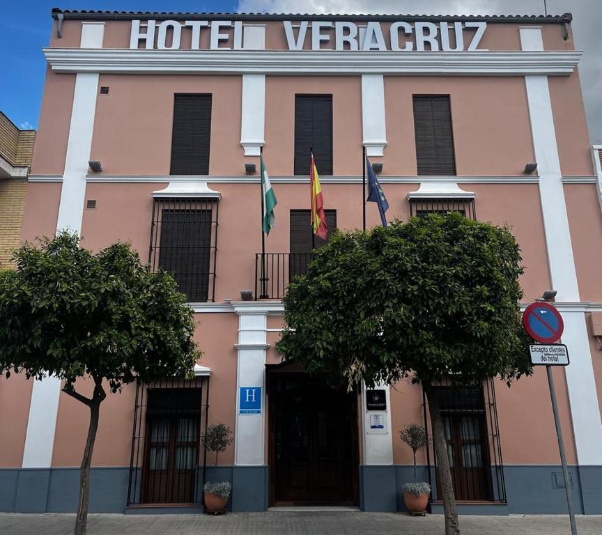 a pink building with two flags in front of it at Hotel Veracruz in Utrera