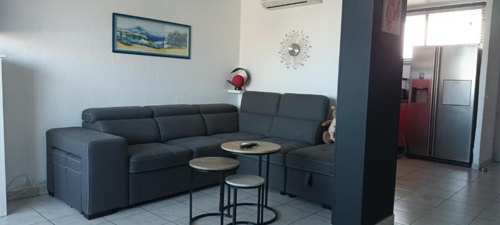 - un salon avec un canapé, une table et des tabourets dans l'établissement Le Queirélé, au Lavandou